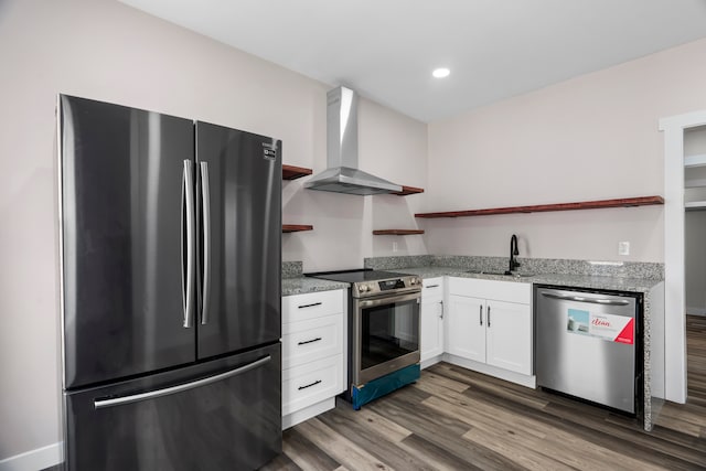 kitchen featuring wall chimney exhaust hood, wood-type flooring, white cabinets, stainless steel appliances, and sink