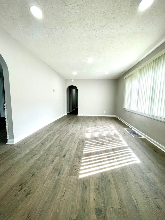 unfurnished living room featuring dark wood-type flooring and a textured ceiling