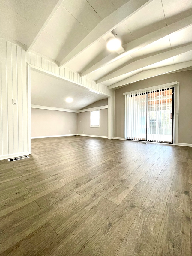 spare room with wood-type flooring and lofted ceiling with beams