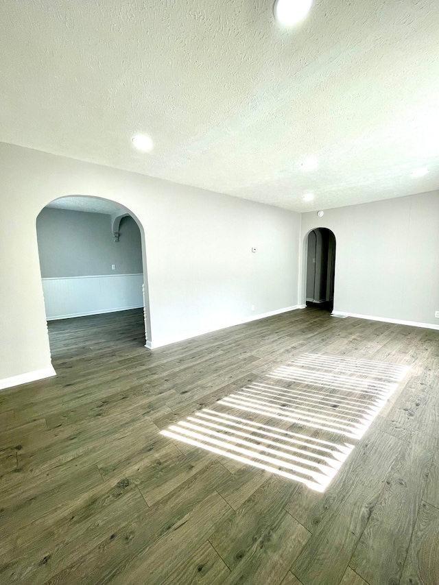 unfurnished living room with dark hardwood / wood-style flooring and a textured ceiling