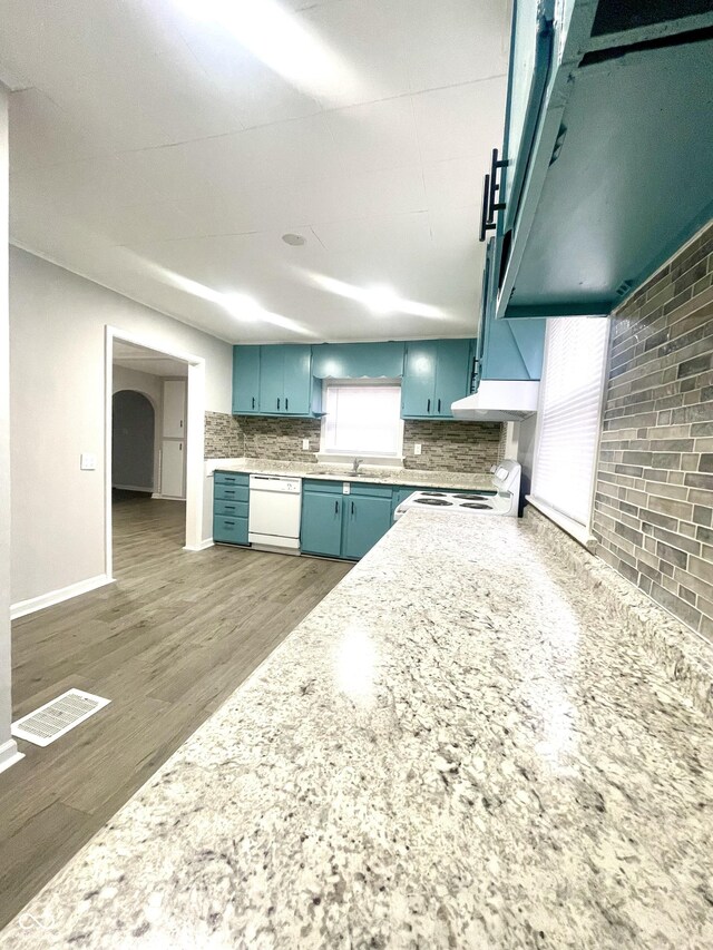 kitchen with sink, dark hardwood / wood-style flooring, decorative backsplash, blue cabinetry, and white appliances