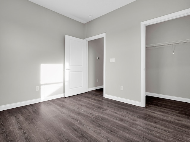 unfurnished bedroom with dark wood-type flooring and a closet