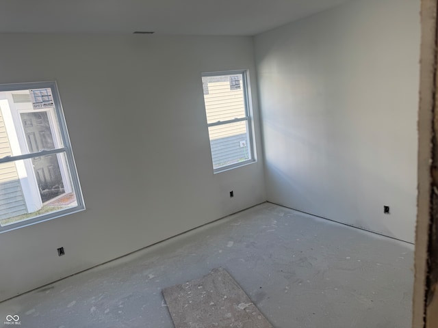 unfurnished room with vaulted ceiling and concrete floors