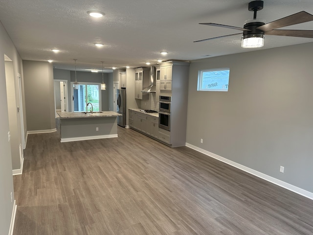 unfurnished living room featuring a textured ceiling, sink, dark wood-type flooring, and ceiling fan