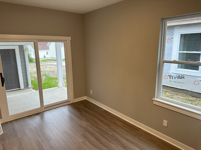 unfurnished room featuring dark hardwood / wood-style floors, a healthy amount of sunlight, and a textured ceiling