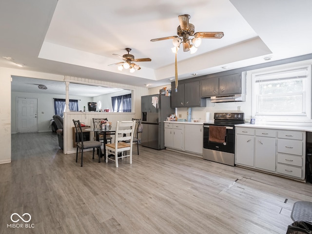 kitchen featuring a raised ceiling, stainless steel fridge, and electric range oven