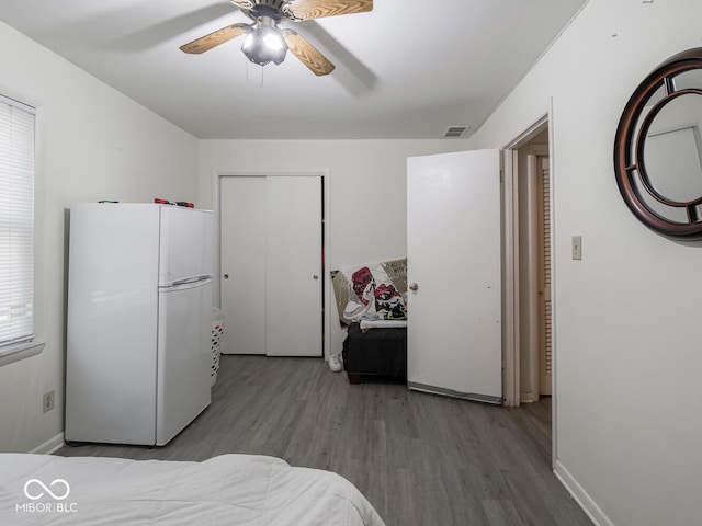 bedroom with ceiling fan, wood-type flooring, and white refrigerator