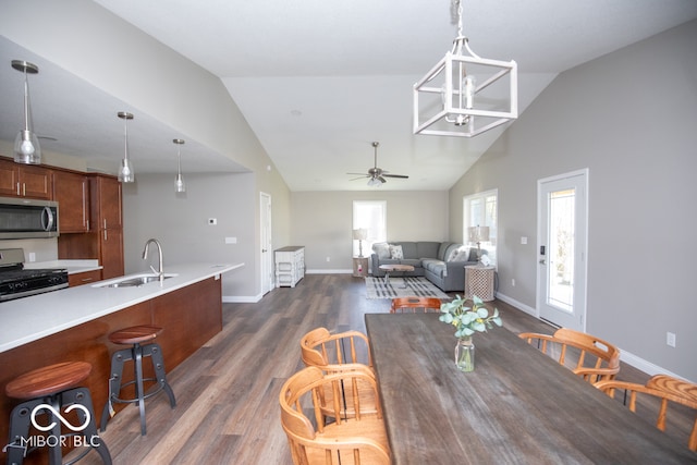 dining room featuring vaulted ceiling, sink, dark wood-type flooring, and ceiling fan with notable chandelier