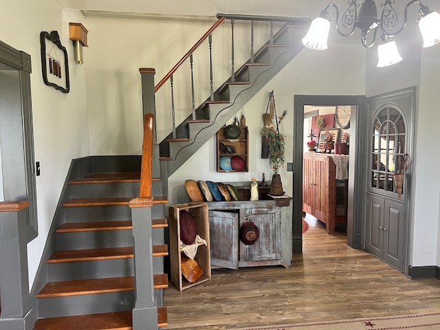 stairs with a notable chandelier and hardwood / wood-style flooring