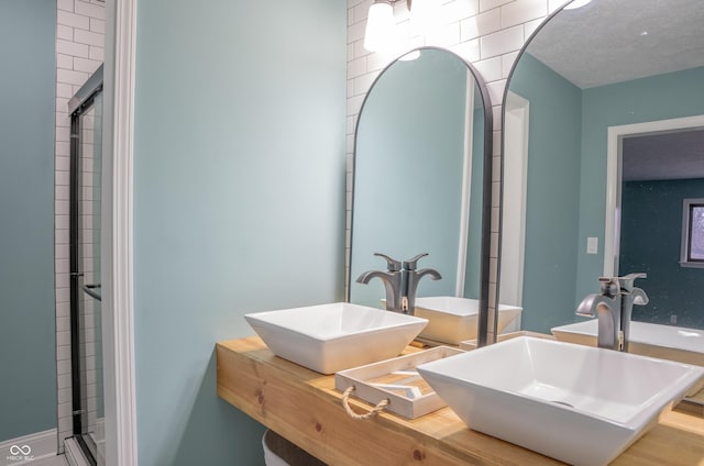 bathroom featuring vanity, a textured ceiling, and a shower with shower door