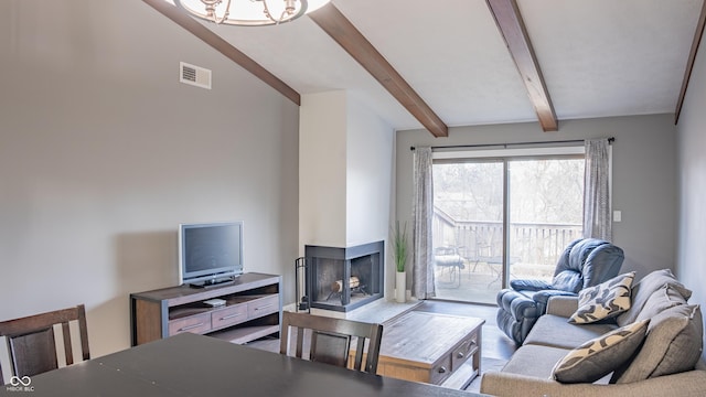 living room with a multi sided fireplace, lofted ceiling with beams, and a chandelier