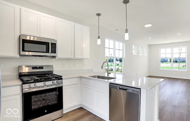 kitchen with stainless steel appliances, white cabinets, kitchen peninsula, and a healthy amount of sunlight