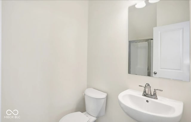 bathroom with walk in shower, sink, and toilet