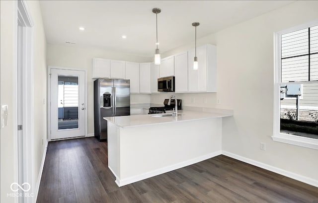 kitchen featuring appliances with stainless steel finishes, kitchen peninsula, dark hardwood / wood-style floors, and white cabinets