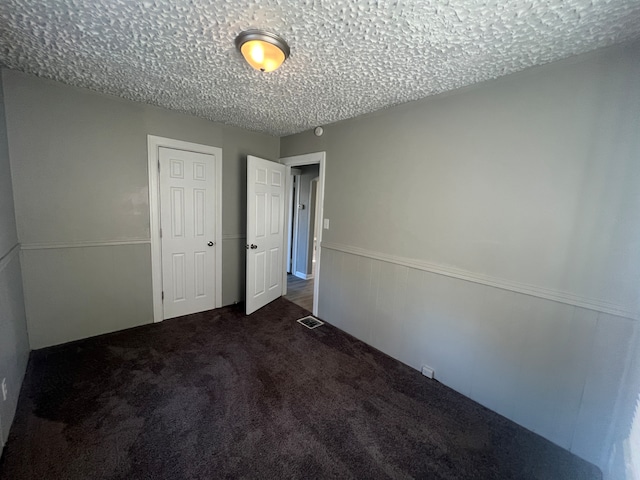 unfurnished bedroom featuring a closet, carpet floors, and a textured ceiling