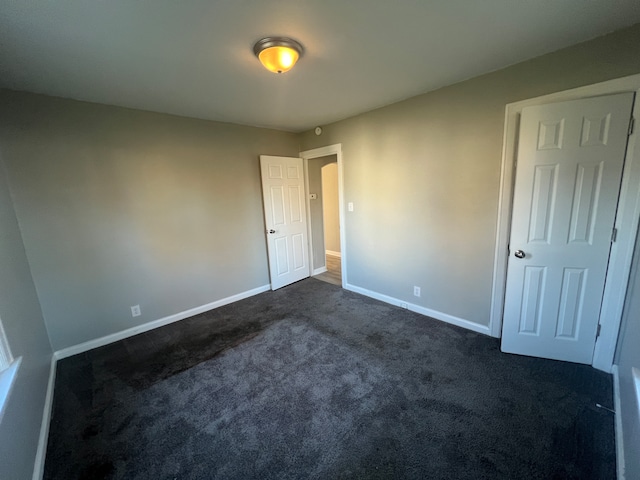 unfurnished bedroom with dark carpet