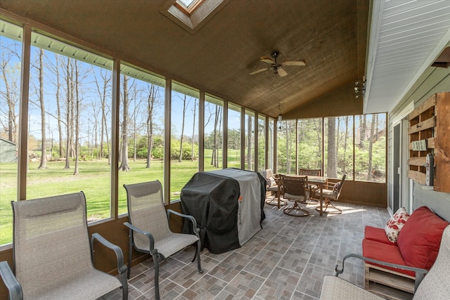 sunroom / solarium with ceiling fan and vaulted ceiling with skylight