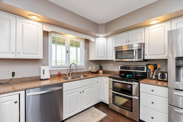 kitchen with sink, appliances with stainless steel finishes, white cabinetry, and dark hardwood / wood-style floors