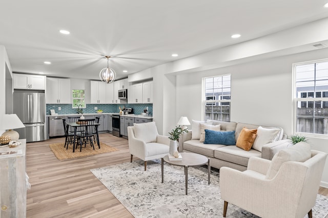 living room with a healthy amount of sunlight, sink, and light hardwood / wood-style floors