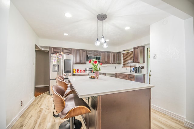 2925 Highwoods Dr, Indianapolis, IN 46222 - kitchen featuring baseboards, a kitchen bar, light wood-type flooring, light countertops, and stainless steel appliances