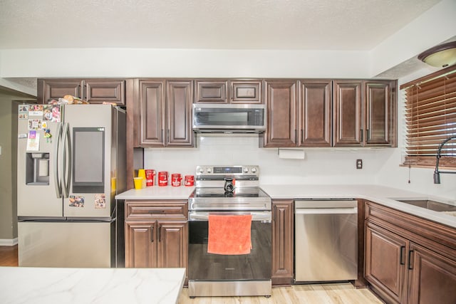 2925 Highwoods Dr, Indianapolis, IN 46222 - kitchen with decorative backsplash, appliances with stainless steel finishes, a sink, light countertops, and light wood-style floors