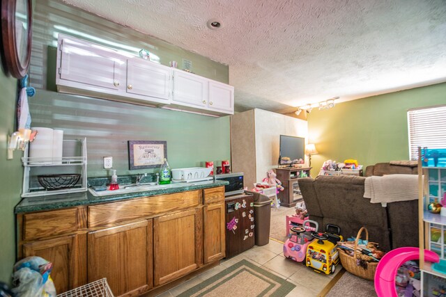 2925 Highwoods Dr, Indianapolis, IN 46222 - kitchen featuring a textured ceiling, dark countertops, brown cabinets, light tile patterned floors, and open floor plan