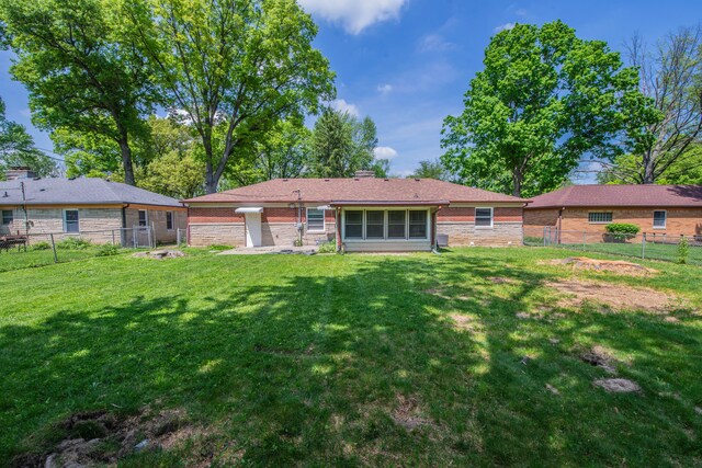 2925 Highwoods Dr, Indianapolis, IN 46222 - back of property featuring a lawn, a fenced backyard, and brick siding