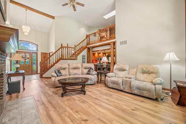 living room with high vaulted ceiling, a fireplace, wood-type flooring, and ceiling fan with notable chandelier