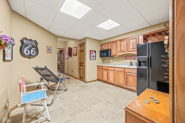 kitchen featuring black appliances, sink, a paneled ceiling, and light tile floors