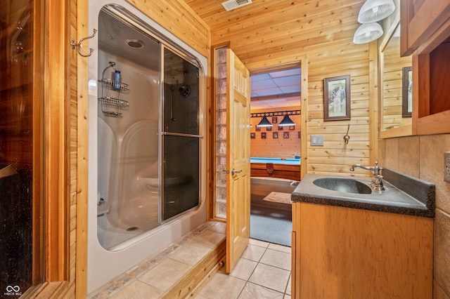 bathroom with tile floors, a shower with shower door, vanity, and wood walls