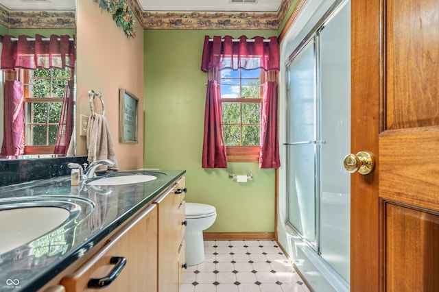 bathroom featuring tile flooring, a healthy amount of sunlight, toilet, and double sink