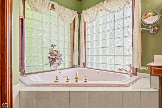 bathroom featuring tiled tub, a wealth of natural light, and vanity