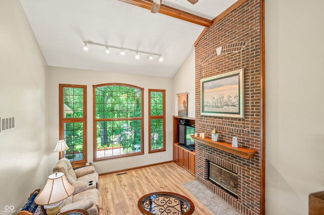 sitting room featuring vaulted ceiling with beams, plenty of natural light, rail lighting, and light hardwood / wood-style flooring