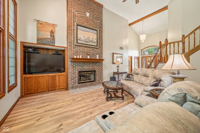 living room featuring high vaulted ceiling, brick wall, light wood-type flooring, and a fireplace