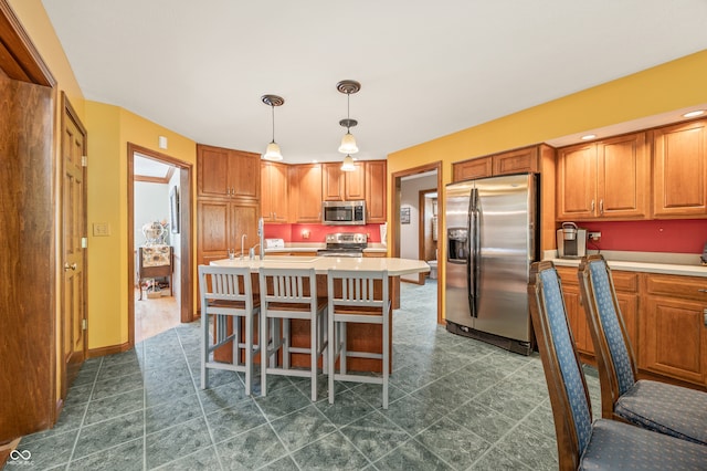 kitchen featuring appliances with stainless steel finishes, decorative light fixtures, dark tile flooring, and a kitchen island