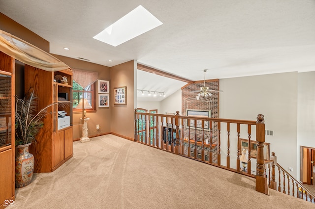 interior space with brick wall, ceiling fan, vaulted ceiling with skylight, and a textured ceiling