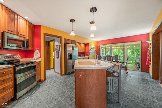 kitchen featuring a center island with sink, appliances with stainless steel finishes, tile floors, pendant lighting, and sink