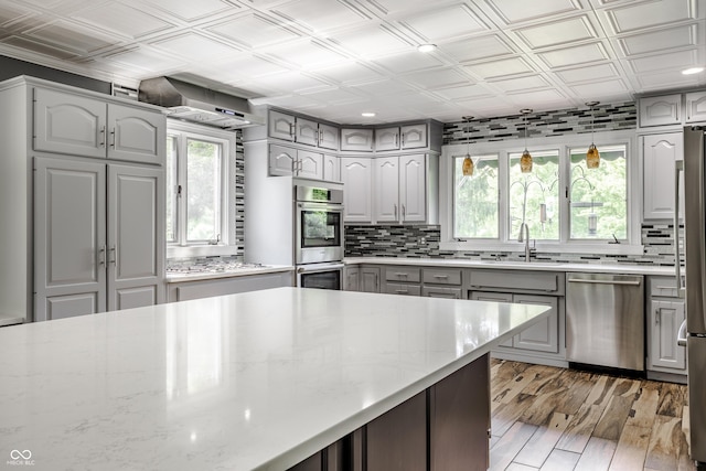 kitchen featuring gray cabinetry, light stone counters, stainless steel appliances, and decorative light fixtures