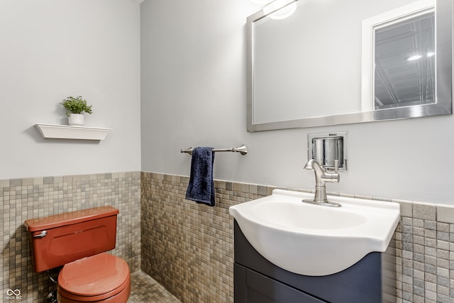 bathroom featuring tile patterned flooring, vanity, toilet, and tile walls