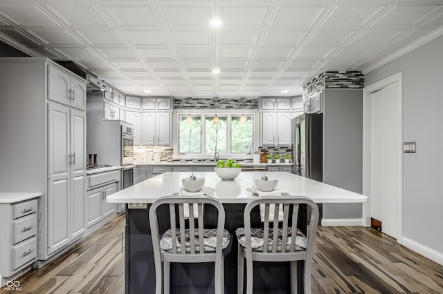 kitchen featuring stainless steel fridge, a breakfast bar, a kitchen island, and wood-type flooring