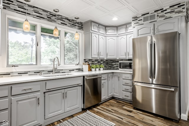 kitchen featuring gray cabinetry, sink, hanging light fixtures, dark hardwood / wood-style flooring, and appliances with stainless steel finishes