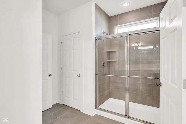 bathroom with a shower with shower door and tile patterned flooring