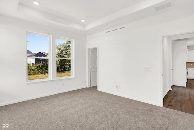 unfurnished room with a raised ceiling and dark hardwood / wood-style flooring