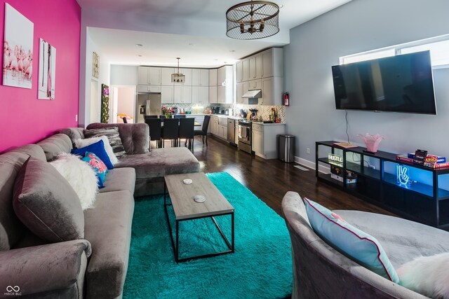 living room with a notable chandelier and dark wood-type flooring