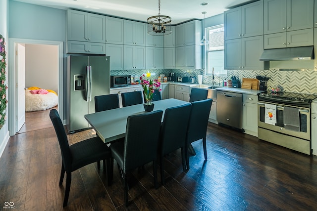 interior space with stainless steel appliances, decorative backsplash, a chandelier, dark wood-type flooring, and hanging light fixtures