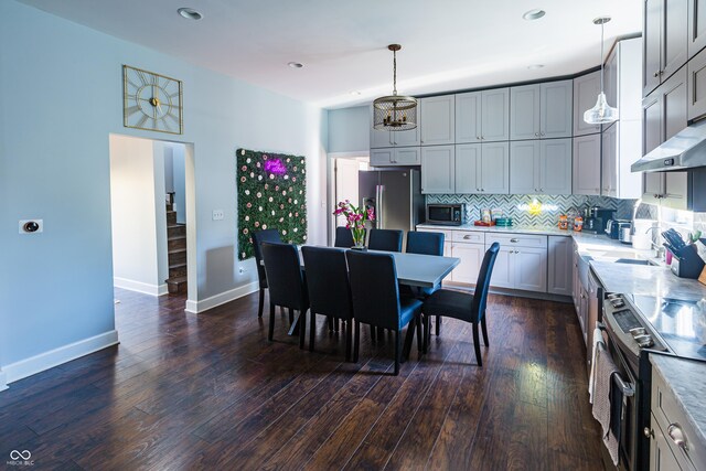 kitchen featuring stainless steel appliances, decorative backsplash, dark hardwood / wood-style floors, gray cabinets, and hanging light fixtures