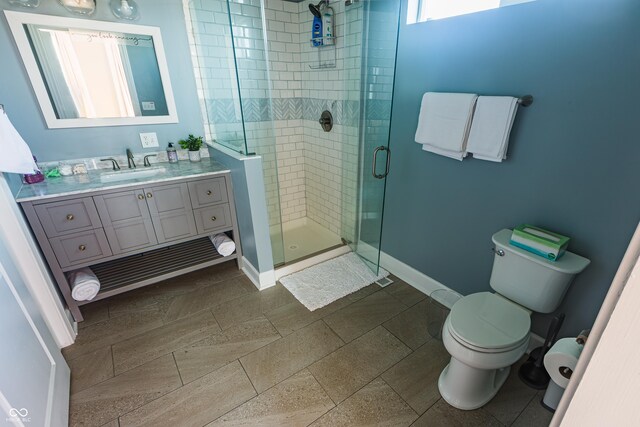 bathroom with an enclosed shower, toilet, vanity, and tile patterned floors