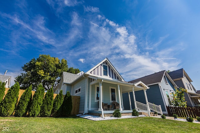 view of front of house featuring covered porch, a front yard, and fence