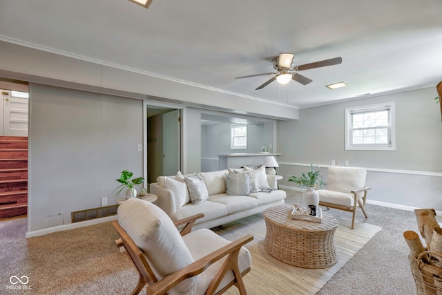 living room featuring ceiling fan, crown molding, and light colored carpet