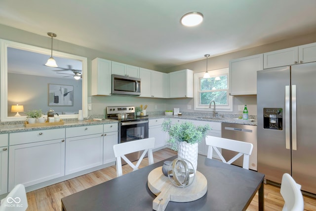 kitchen featuring white cabinetry, stainless steel appliances, ceiling fan, and light hardwood / wood-style floors